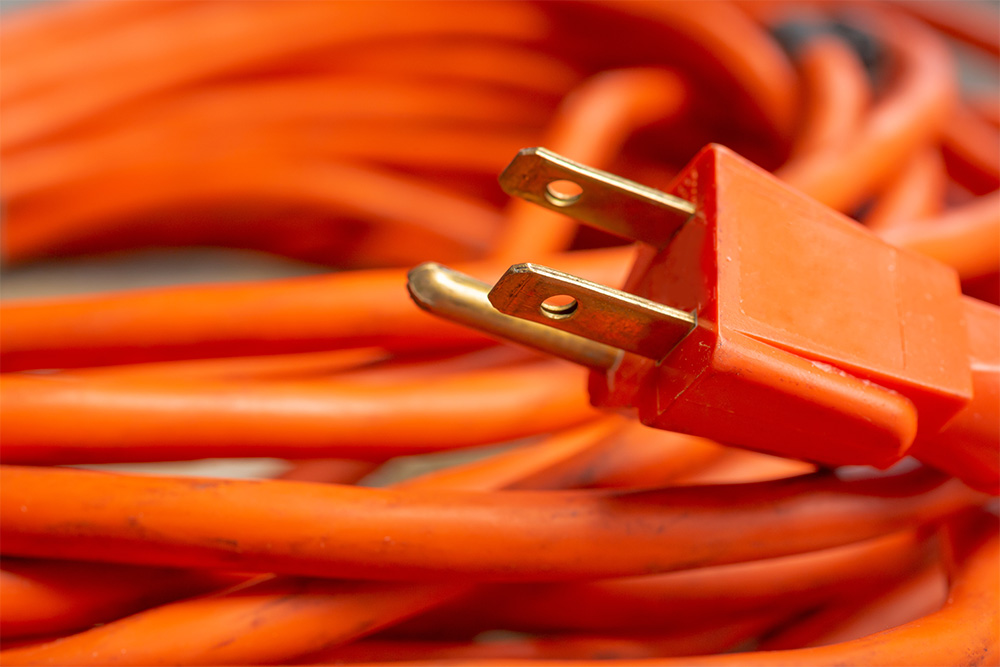 A closeup view of a male end plug of a coiled orange extension c