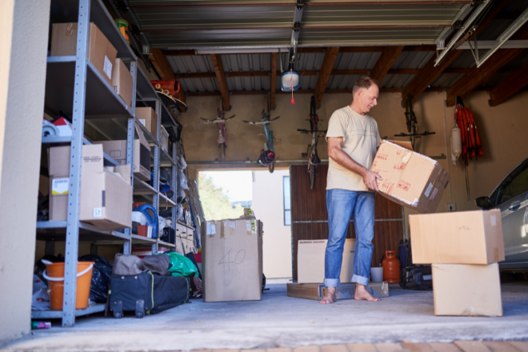 A man shuffling boxes around his garage as part of summer cleaning.