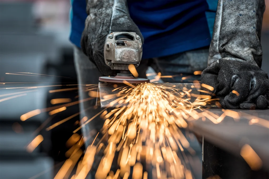 A metal fabricator grinding a metal beam