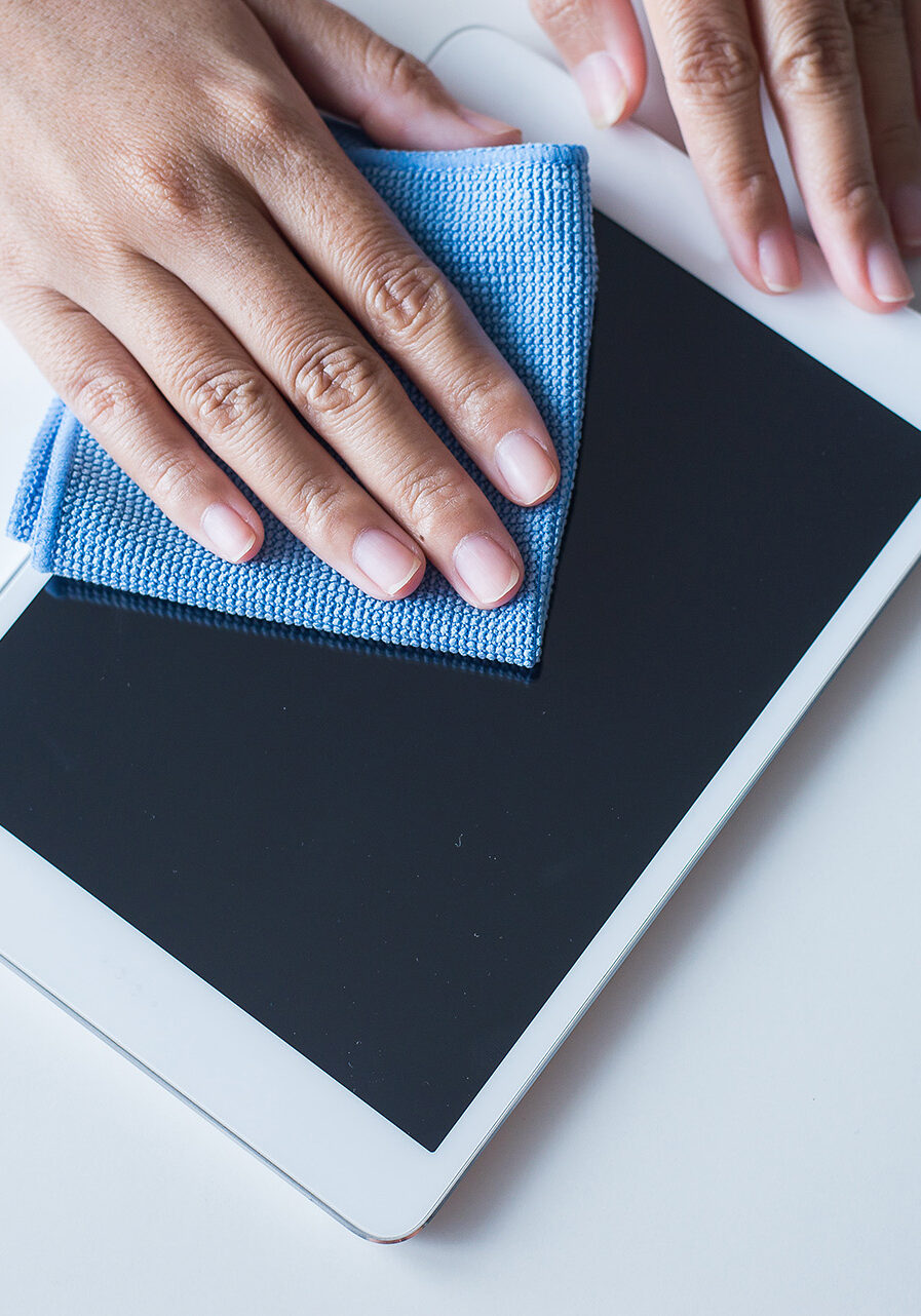 Hand female cleaning dirty her tablet on screen with microfiber cloth